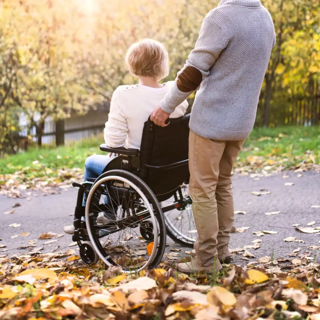 Man pushing woman in wheelchair outside during fall