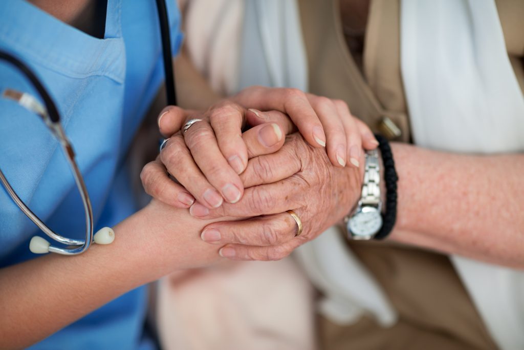 Nurse consoling and holding hands of an old woman