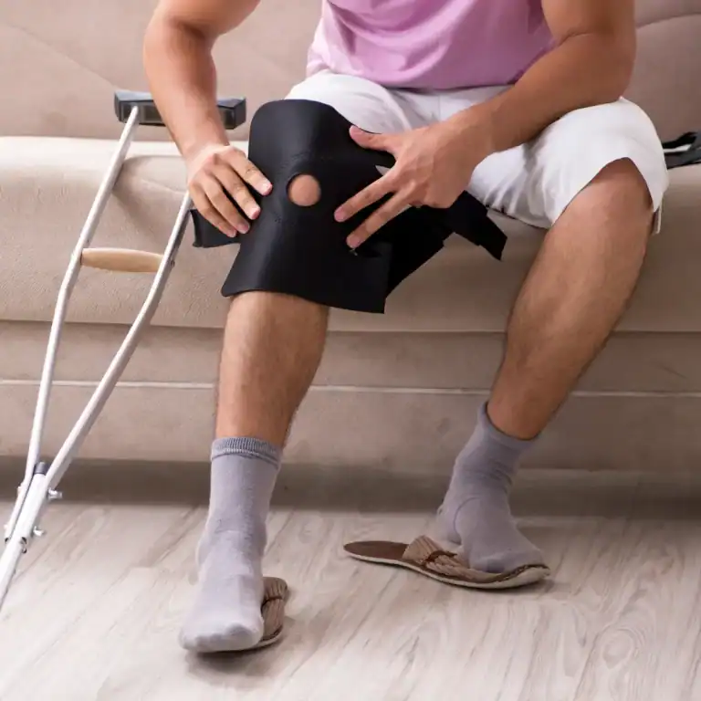 person putting on a knee brace while sitting on the couch